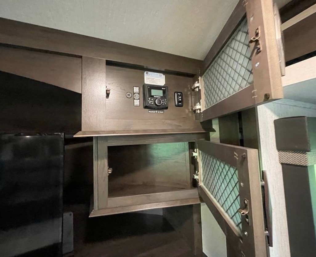 Bedroom storage area with built-in cabinets, control panels, and organized compartments