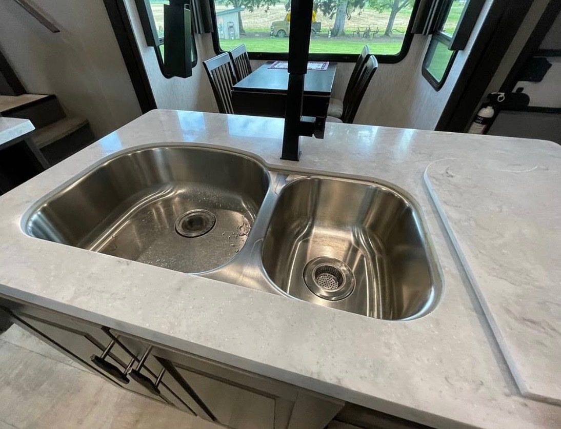 Dual-basin stainless steel kitchen sink with modern faucet in marble countertop