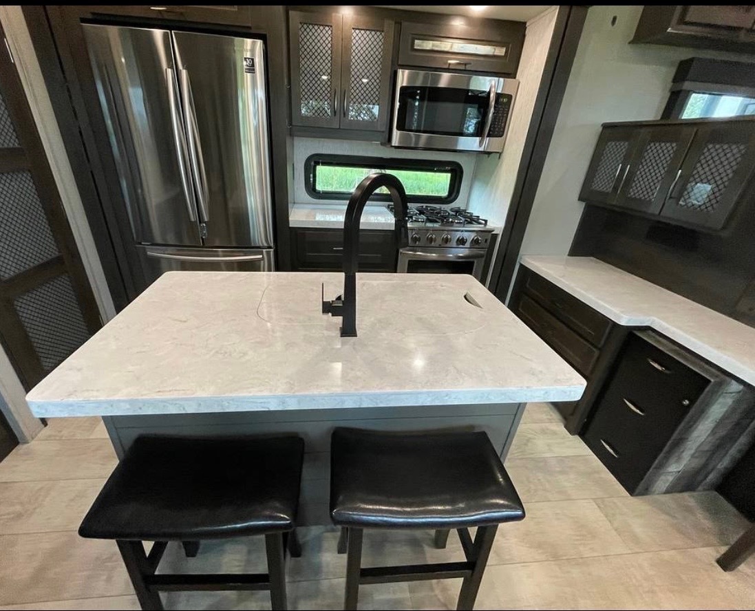 Kitchen island with marble countertop, modern black faucet, and bar seating
