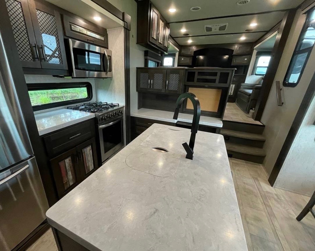 Wide view of gourmet kitchen showing full layout with stainless appliances and dark cabinetry