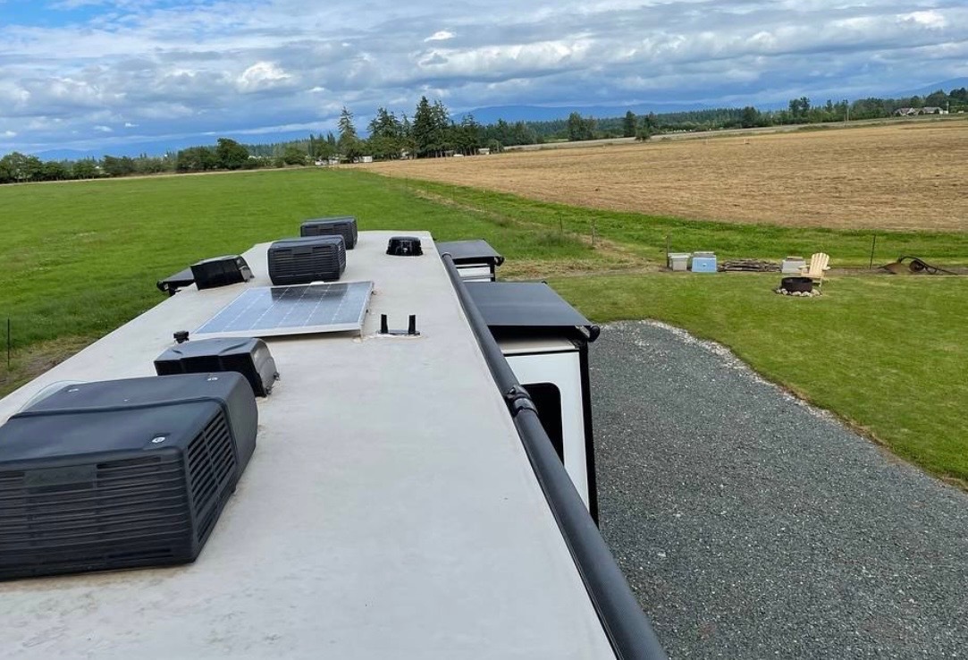 Rooftop view showing solar panels, dual A/C units, and ventilation systems